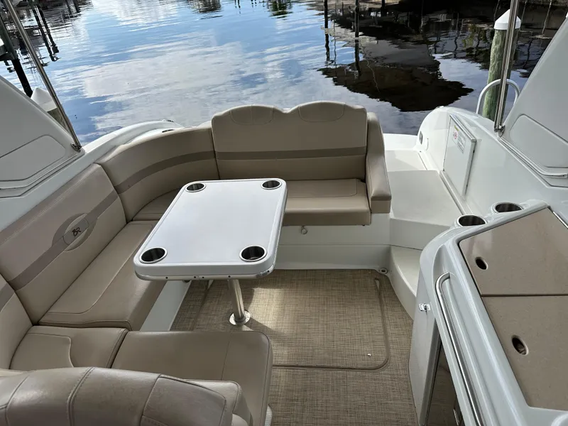 Slide: The Image of 2009 Formula 310 Bowrider interior with beige seating and table, docked by calm water. - 8