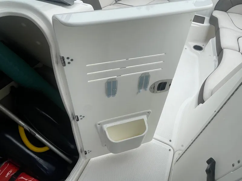 Slide: The Image of 2020 Yamaha Boats 242 Limited S interior storage compartment with open door and visible accessories. - 13