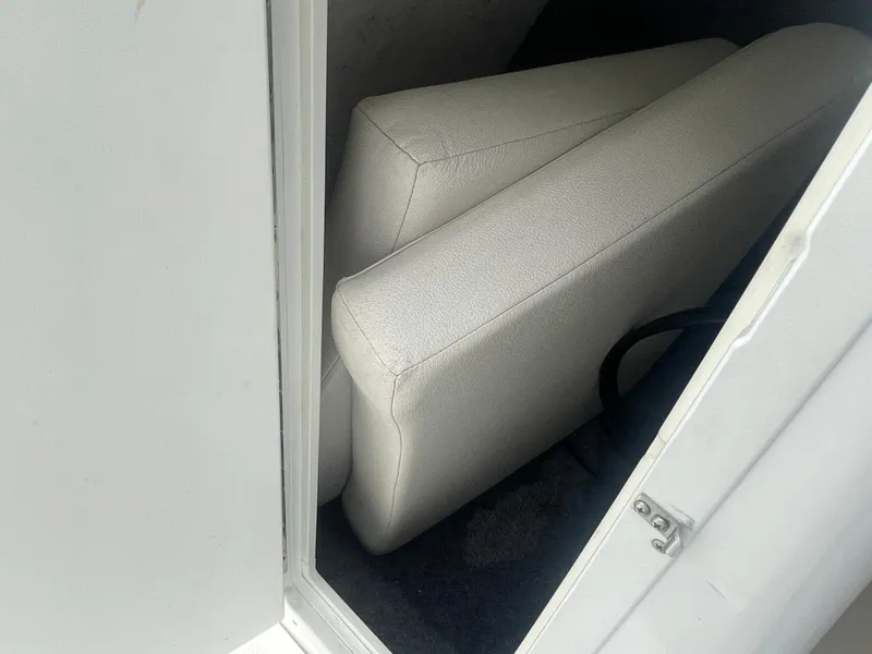 Slide: The Image of 2020 Yamaha Boats 242 Limited S storage compartment with white cushions. - 14