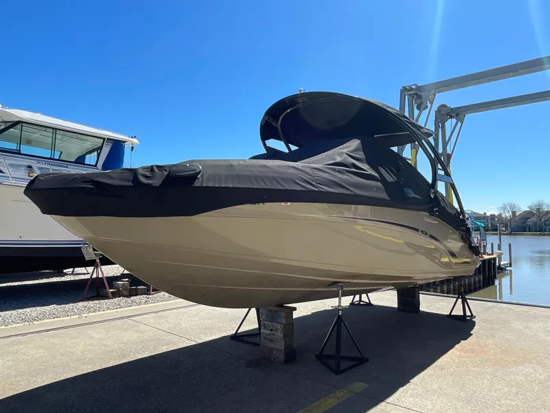 Slide: The Image of 2020 Yamaha Boats 242 Limited S covered and docked by the water. - 2