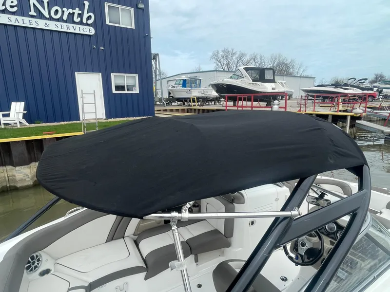 Slide: The Image of 2020 Yamaha Boats 242 Limited S with black canopy at a marina. - 22