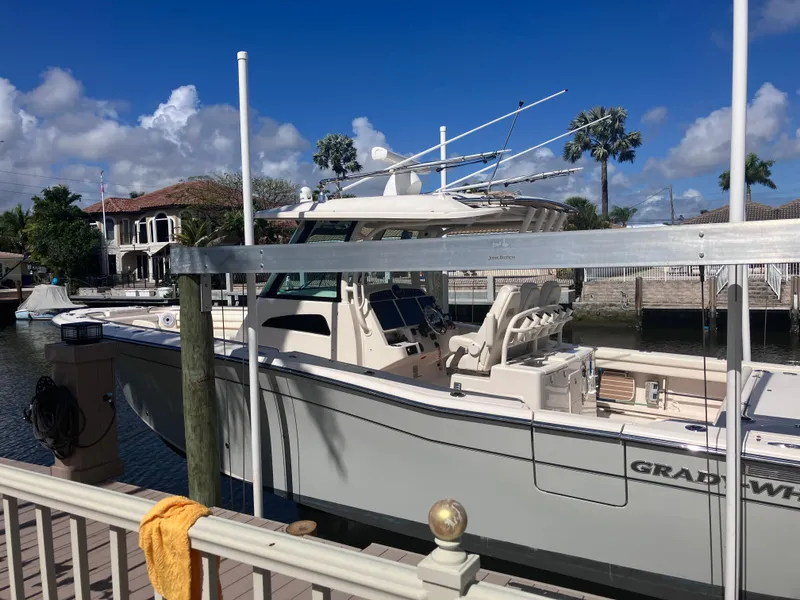 Slide: The Image of 2020 Grady-White Canyon 336 boat docked by waterfront homes under a clear blue sky. - 10