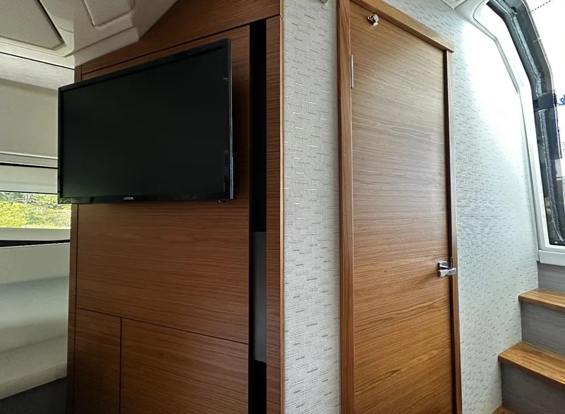 Slide: The Image of 2024 Tiara Yachts 43 LE interior with wood paneling and mounted TV. - 20