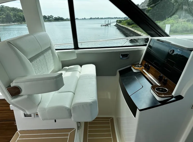 Slide: The Image of 2024 Tiara Yachts 43 LE helm with luxurious seating and modern controls, overlooking serene waters. - 5