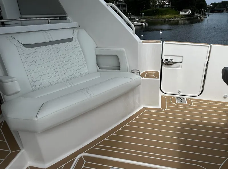 Slide: The Image of 2024 Tiara Yachts 43 LE interior with white seating and teak flooring by the water. - 6