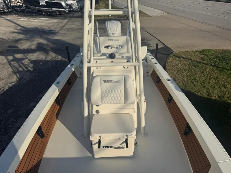 Slide: The Image of 2025 Pathfinder 2500 Hybrid boat interior with seating and console, docked on a sunny day. - 11
