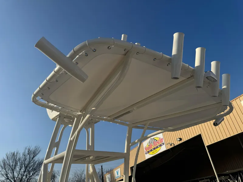 Slide: The Image of T-top of 2025 Pathfinder 2500 Hybrid boat with rod holders against clear blue sky. - 39