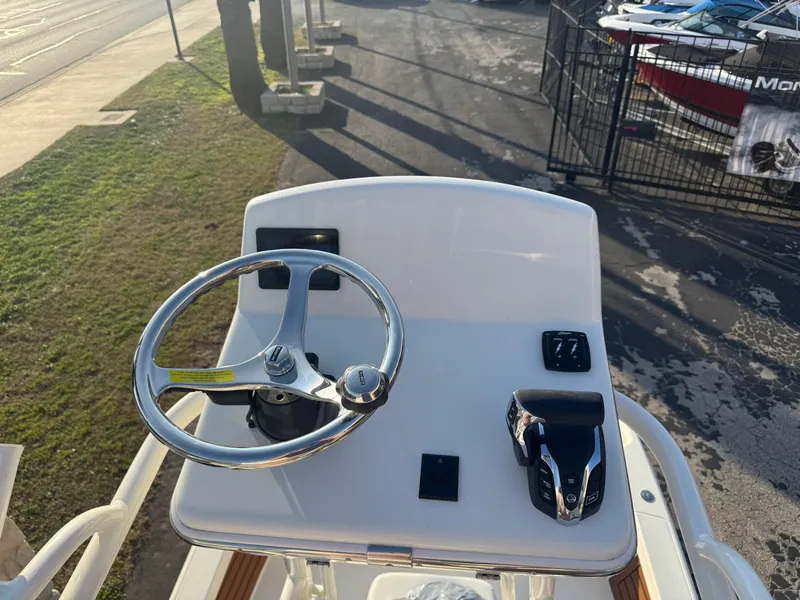 Slide: The Image of 2025 Pathfinder 2500 Hybrid boat helm with steering wheel and controls, docked outdoors. - 46
