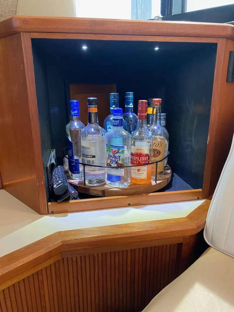 Slide: The Image of Liquor cabinet on 1990 Viking 45 Convertible yacht with assorted bottles and wood finish. - 11
