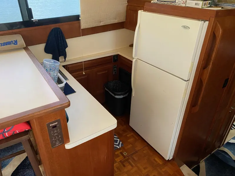 Slide: The Image of 1990 Viking 45 Convertible yacht kitchen with white refrigerator and wooden cabinetry. - 14