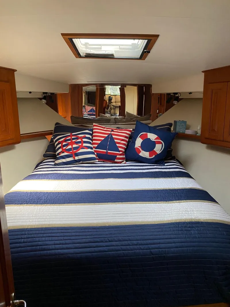 Slide: The Image of Nautical-themed bedroom in 1990 Viking 45 Convertible yacht with striped bedding and decorative pillows. - 19