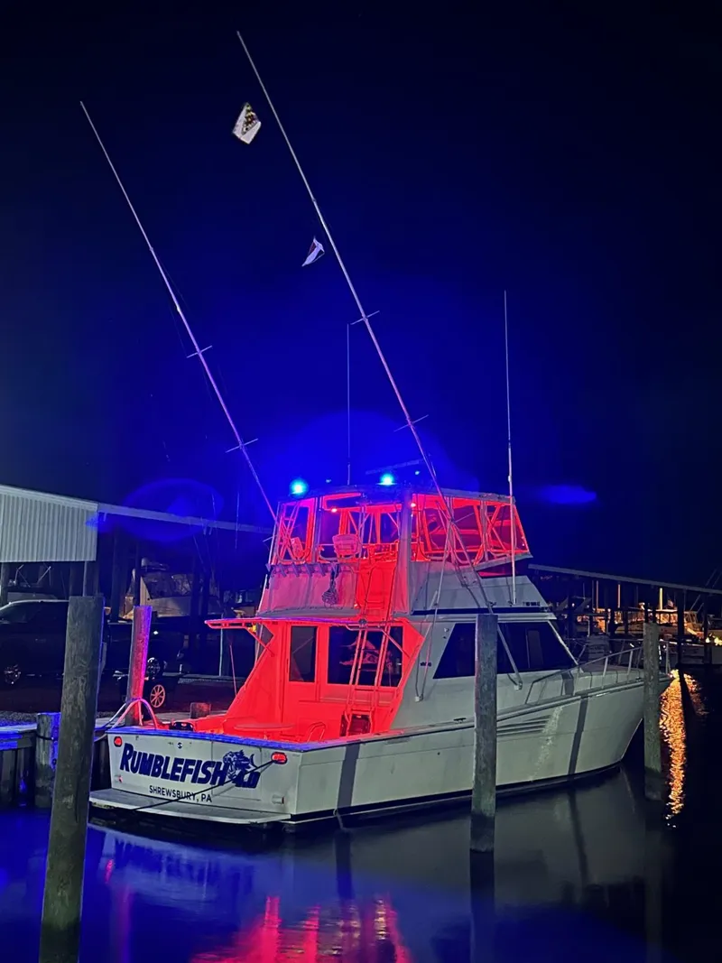 Slide: The Image of 1990 Viking 45 Convertible boat illuminated at night with vibrant red and blue lights. - 2