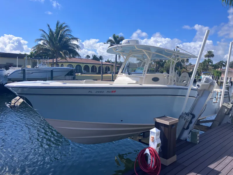 Slide: The Image of 2018 Grady-White Canyon 336 boat docked by palm trees under a clear blue sky. - 3