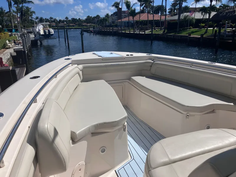Slide: The Image of 2018 Grady-White Canyon 336 boat interior with cushioned seating, docked by a scenic waterfront. - 41