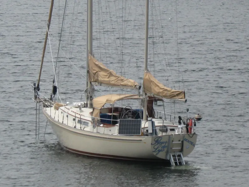 Slide: The Image of 1983 Whitby 42 Ketch sailboat on calm water, featuring tan sails and solar panel. - 2