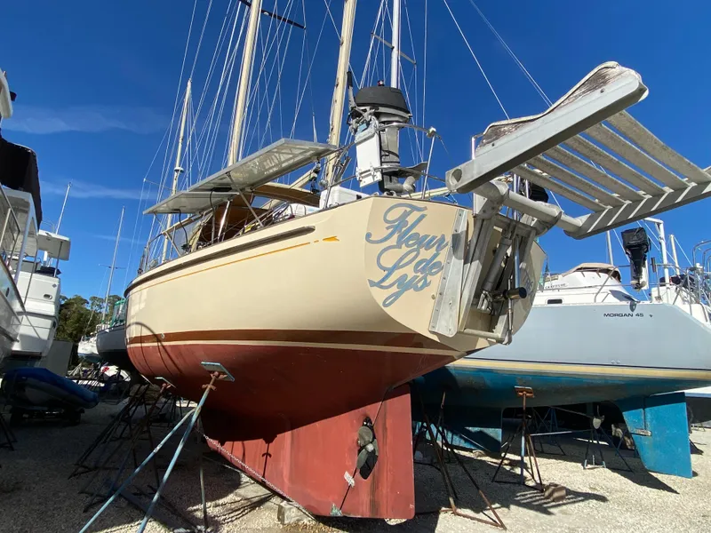 Slide: The Image of 1983 Whitby 42 Ketch sailboat on dry dock, showcasing hull and rigging under clear blue sky. - 24