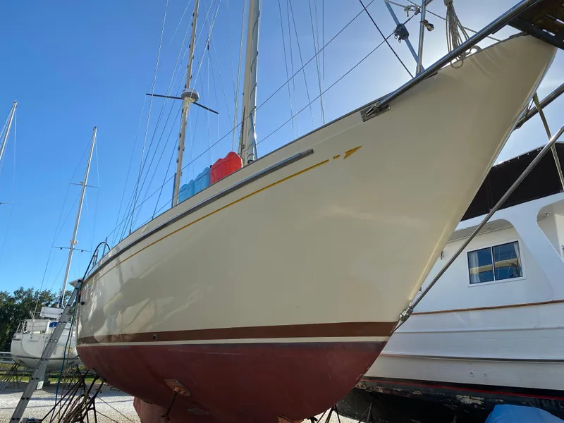 Slide: The Image of 1983 Whitby 42 Ketch sailboat on dry dock, side view under clear blue sky. - 26