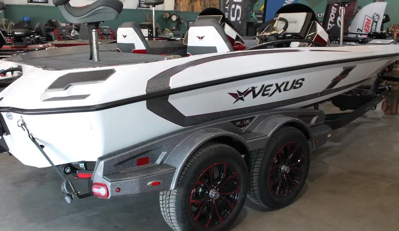 Slide: The Image of 2025 Vexus VXS21 boat with sleek design and dual-axle trailer in showroom. - 1