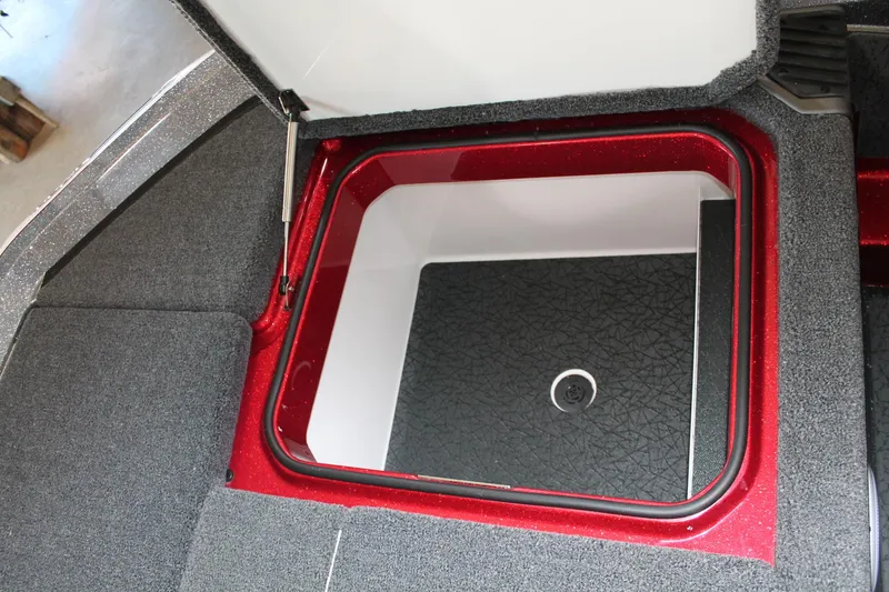 Slide: The Image of Open storage compartment in 2025 Vexus VXS21 boat, featuring red trim and carpeted interior. - 21