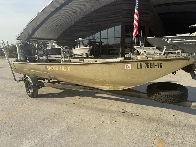 Slide: The Image of 2003 Gator Trax 20' boat on trailer, parked outside a building with an American flag. - 7