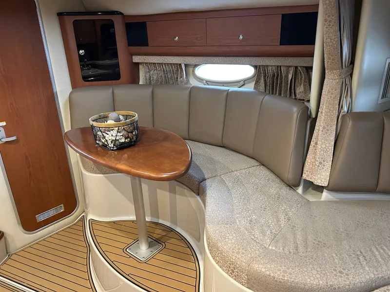 Slide: The Image of Interior of 2003 Chaparral 330 Signature Cruiser with curved seating and wooden table. - 18