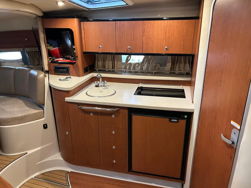 Slide: The Image of 2003 Chaparral 330 Signature Cruiser interior with kitchenette, wood cabinets, and compact appliances. - 22