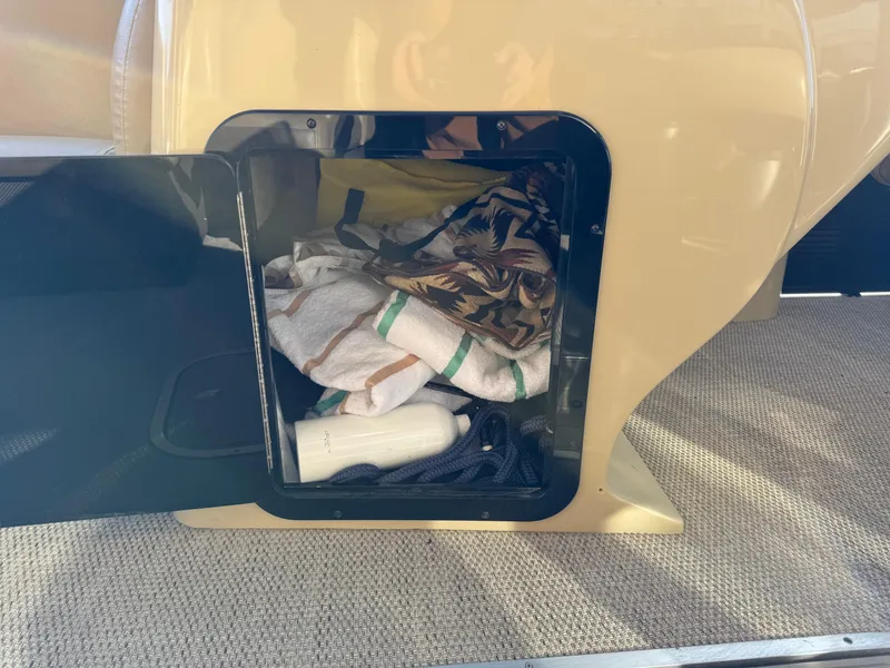 Slide: The Image of Storage compartment of 2019 Godfrey Premium 235SD Sundeck with towels and accessories. - 16