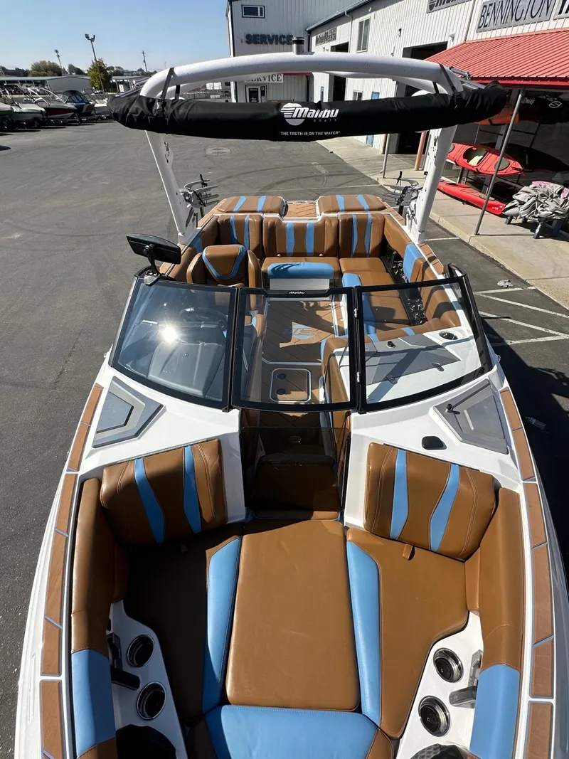 Slide: The Image of 2024 Malibu 22 LSV boat with brown and blue interior, parked outdoors. - 11
