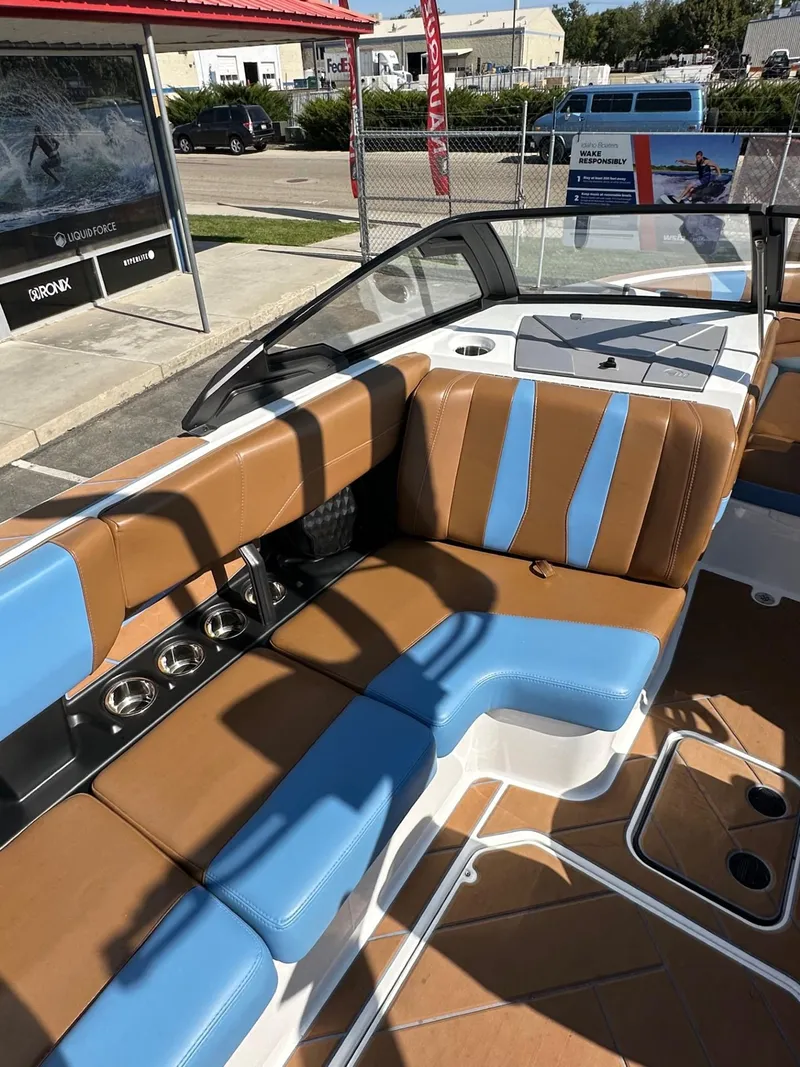 Slide: The Image of 2024 Malibu 22 LSV boat interior with brown and blue seating, cup holders, and modern design. - 14