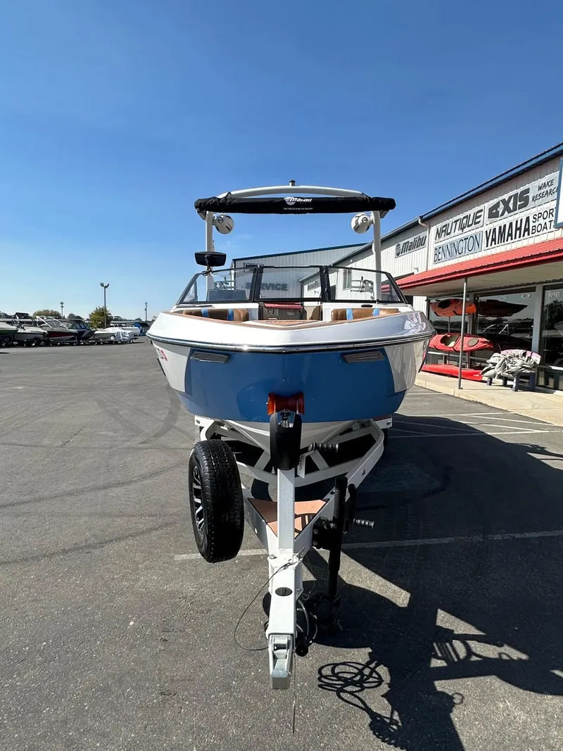 Slide: The Image of 2024 Malibu 22 LSV boat on trailer, parked outside dealership under clear blue sky. - 4