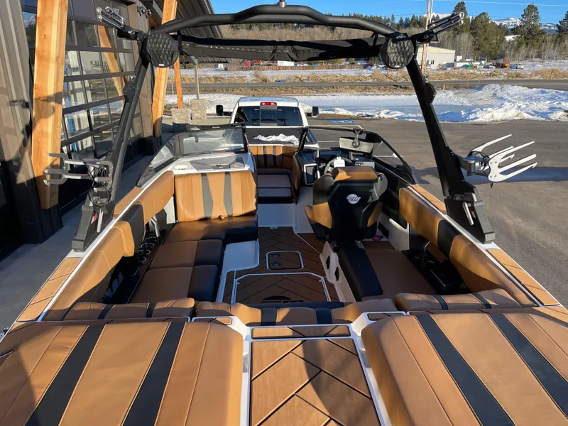 Slide: The Image of 2024 Malibu 22 LSV boat interior with tan and black seating, parked outdoors. - 5