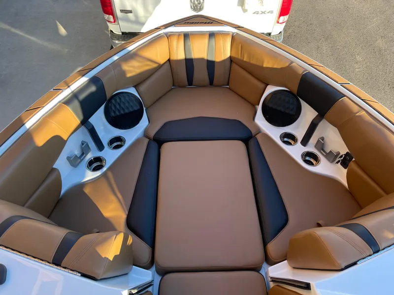 Slide: The Image of 2024 Malibu 22 LSV boat interior with tan and black seating, cup holders, and speakers. - 7