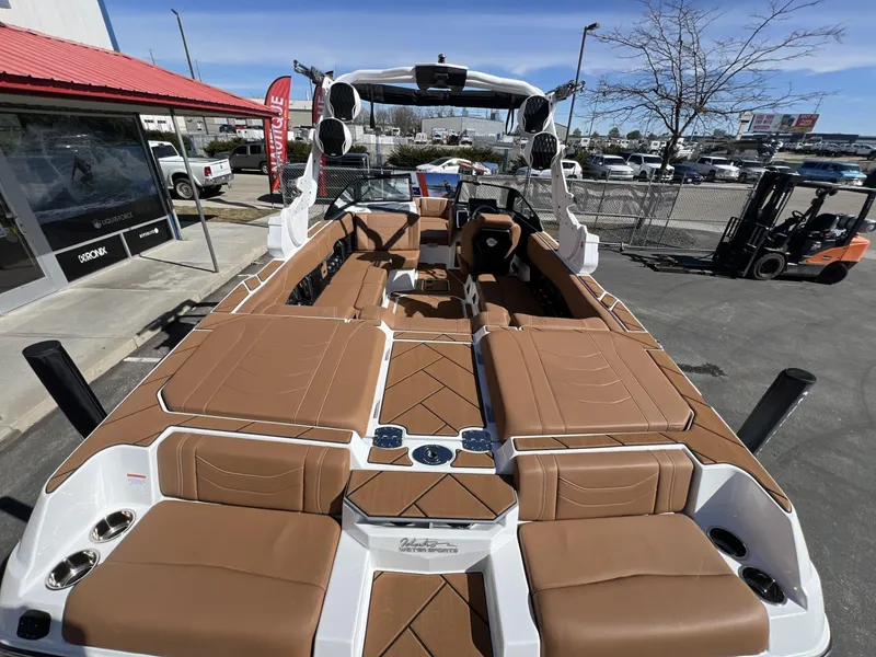Slide: The Image of 2024 Malibu 23 LSV boat with tan seating and modern design in a dealership lot. - 11