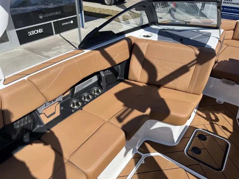 Slide: The Image of 2024 Malibu 23 LSV boat interior with tan leather seating and cup holders. - 14