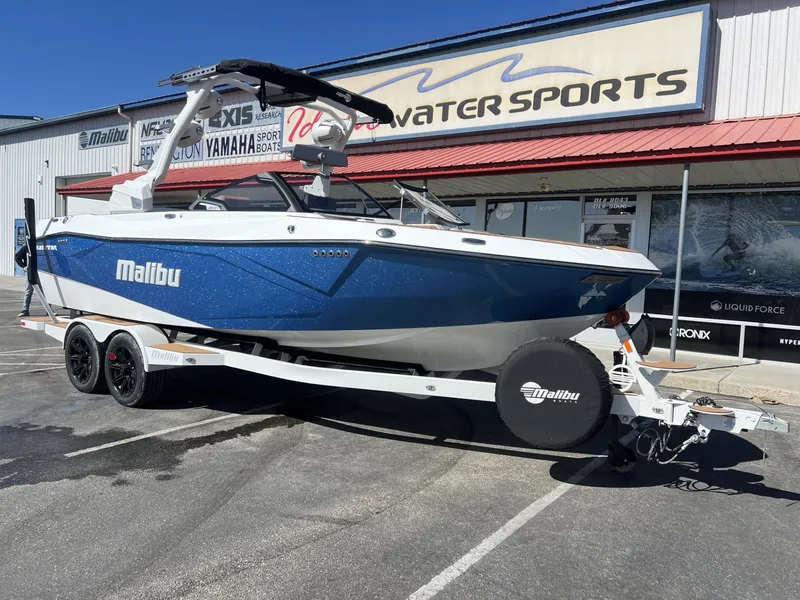 Slide: The Image of 2024 Malibu 23 LSV boat on trailer outside a water sports store. - 3