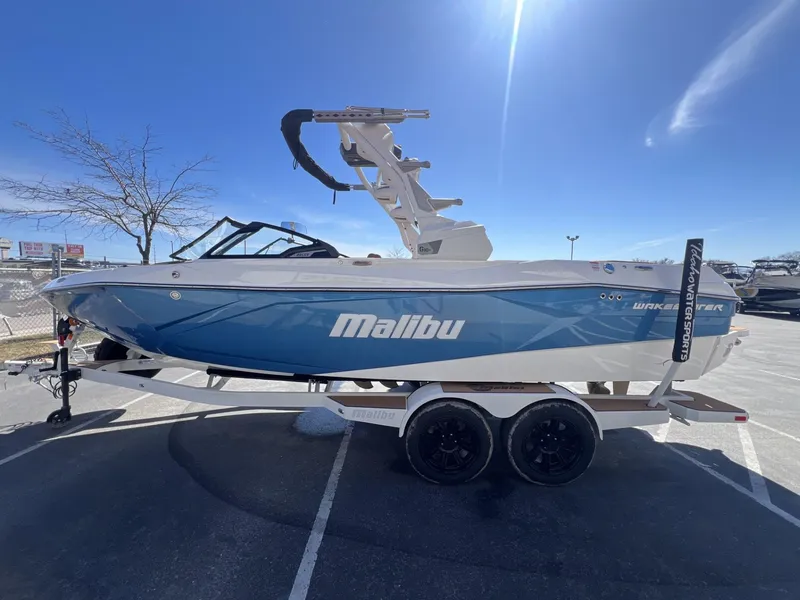 Slide: The Image of 2024 Malibu 23 LSV boat in blue and white on a trailer under a clear sky. - 6