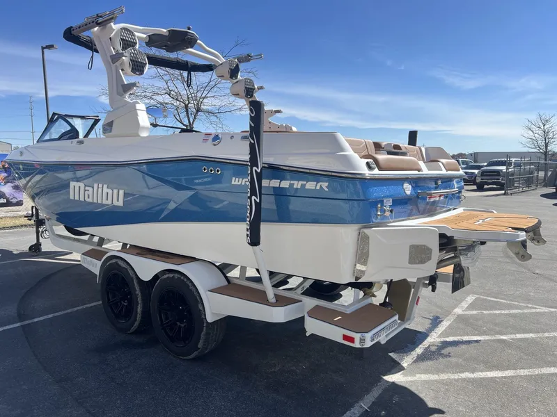 Slide: The Image of 2024 Malibu 23 LSV boat on trailer, blue and white design, parked outdoors. - 7