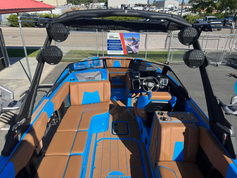 Slide: The Image of 2024 Malibu 24 MXZ boat interior with blue and tan seating, advanced dashboard, and speakers. - 12