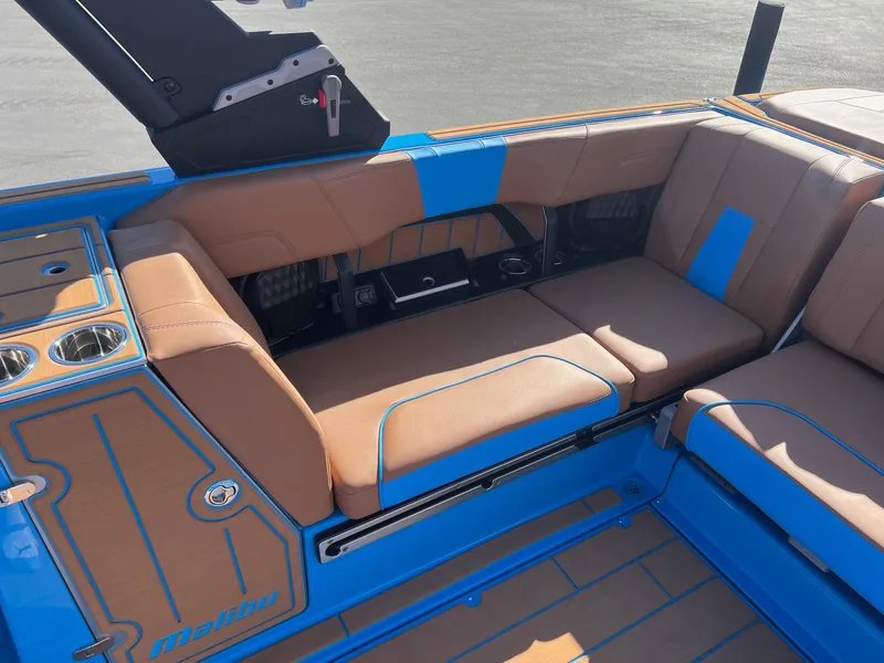 Slide: The Image of 2024 Malibu 24 MXZ boat interior with tan and blue seating, cup holders, and sleek design. - 14