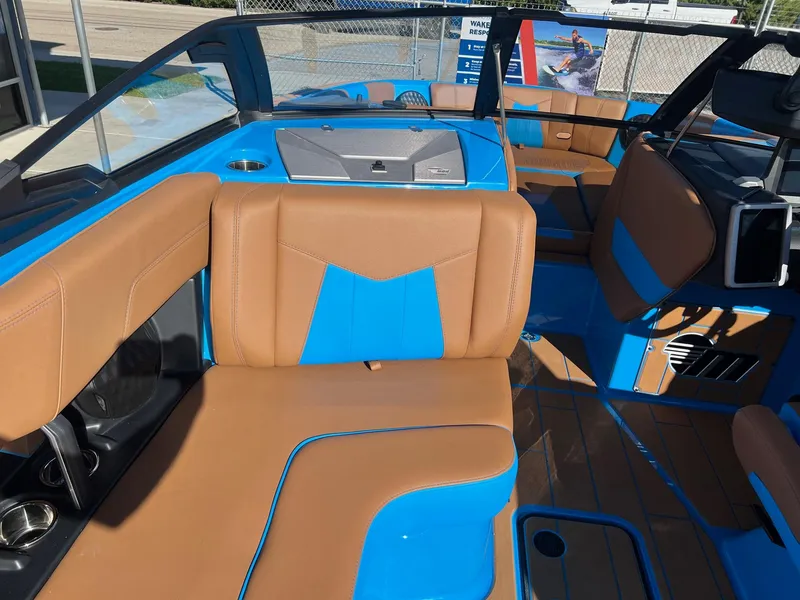 Slide: The Image of 2024 Malibu 24 MXZ boat interior with blue and tan seating, modern design. - 15