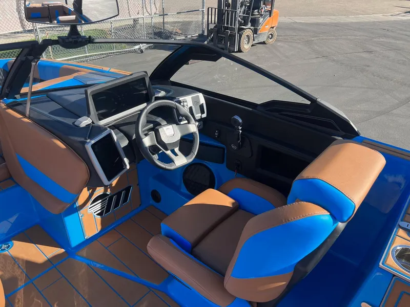 Slide: The Image of 2024 Malibu 24 MXZ boat interior with blue and brown seating, modern dashboard, and steering wheel. - 16