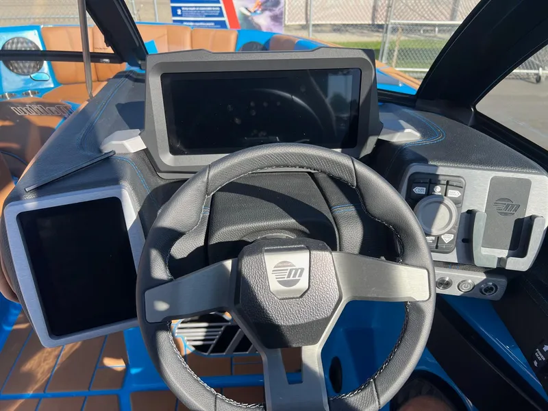 Slide: The Image of 2024 Malibu 24 MXZ boat dashboard with steering wheel and digital displays. - 17