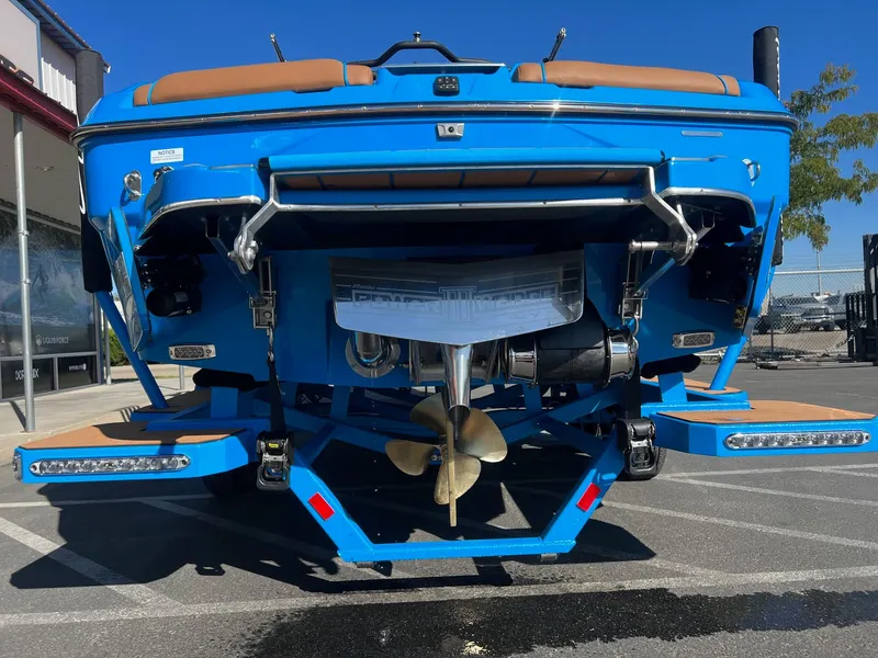 Slide: The Image of 2024 Malibu 24 MXZ boat, rear view, vibrant blue color, parked outdoors. - 9