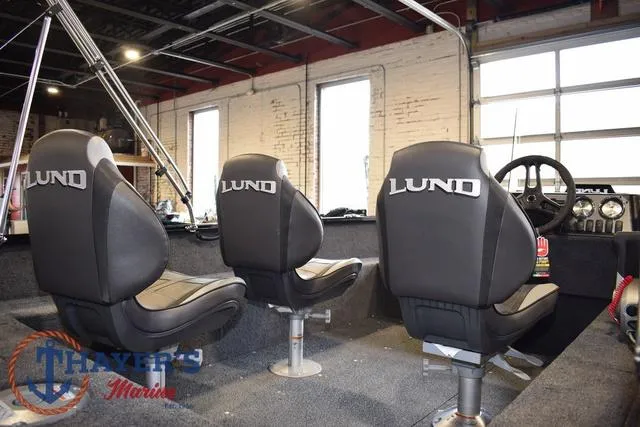 Slide: The Image of 2025 Lund 1650 Rebel XL SS boat interior with three branded seats in a showroom. - 11