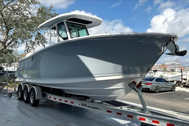 Slide: The Image of 2025 Blackfin 272CC boat on trailer, parked outdoors under a blue sky. - 2