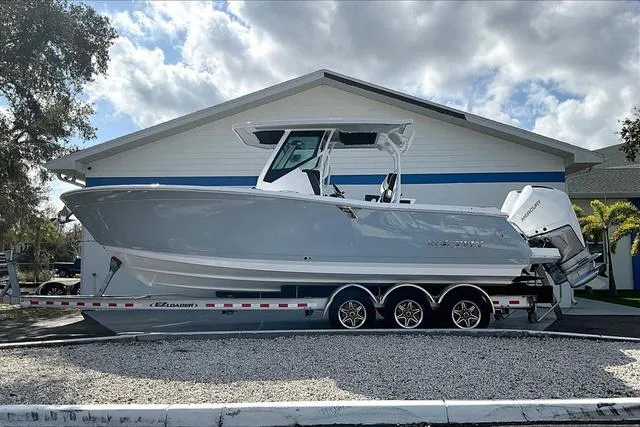 Slide: The Image of 2025 Blackfin 272CC boat on trailer, parked outdoors, under cloudy sky. - 3