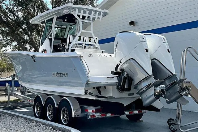 Slide: The Image of 2025 Blackfin 272CC boat on trailer with dual engines, parked outdoors. - 4