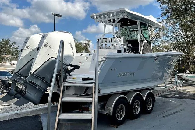 Slide: The Image of 2025 Blackfin 272CC boat on trailer, featuring dual outboard engines, under a clear blue sky. - 6