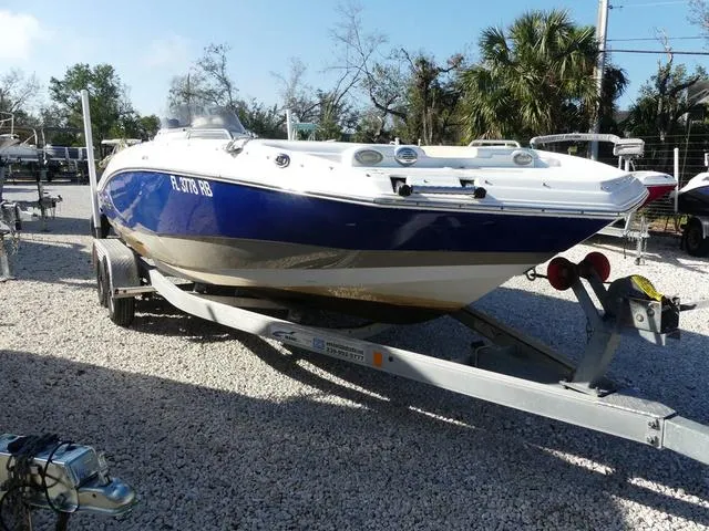 Slide: The Image of 2016 NauticStar 203 DC boat on trailer, parked on gravel, surrounded by trees. - 3