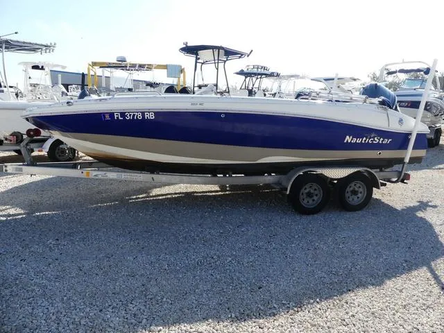 Slide: The Image of 2016 NauticStar 203 DC boat on trailer, blue and white design, parked on gravel. - 4